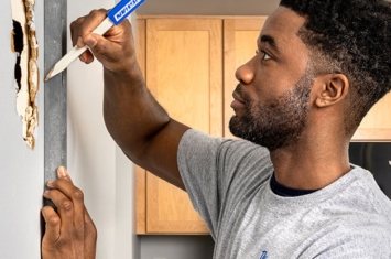Man repairing drywall inside home