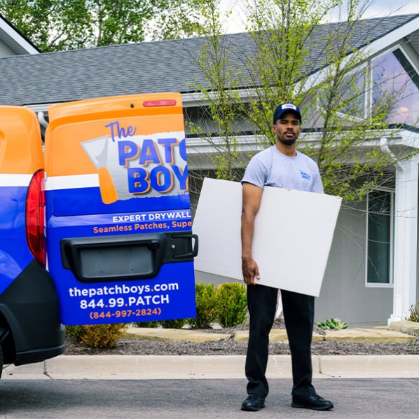 Patch Boys technician holding drywall by van